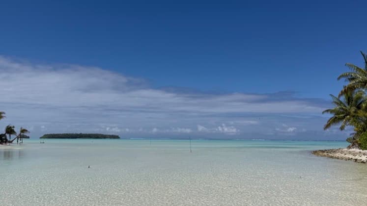 a white sand beach with crystal clear water and palms overlooking the ocean in Tetra atop in French Polynesia